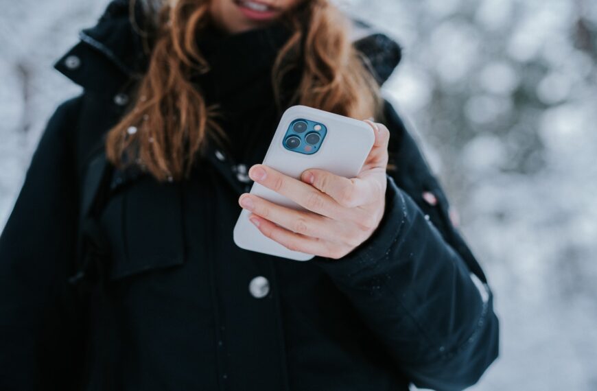 woman in black coat holding white and blue ceramic mug