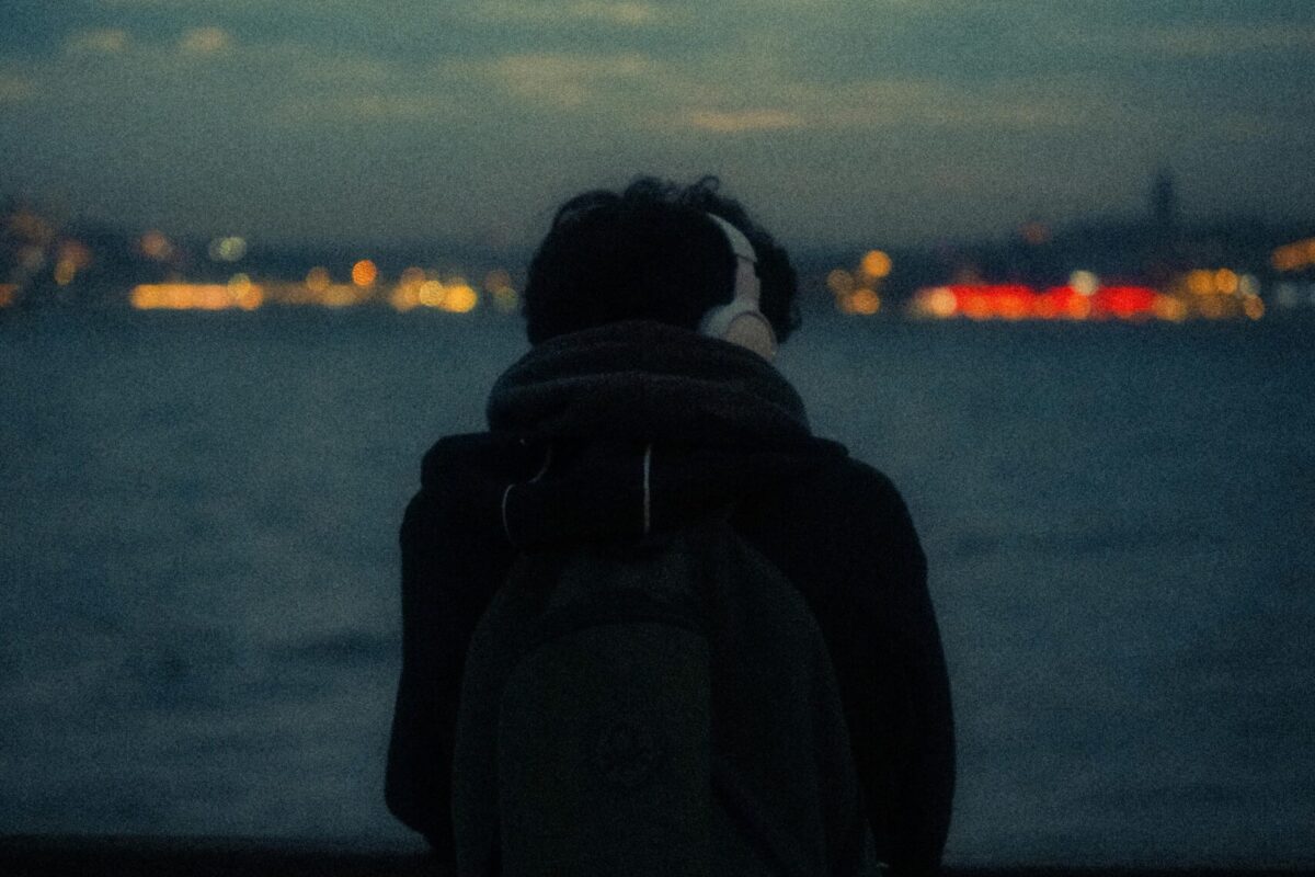 Backpacker wearing headphones overlooking water