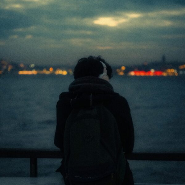 Backpacker wearing headphones overlooking water