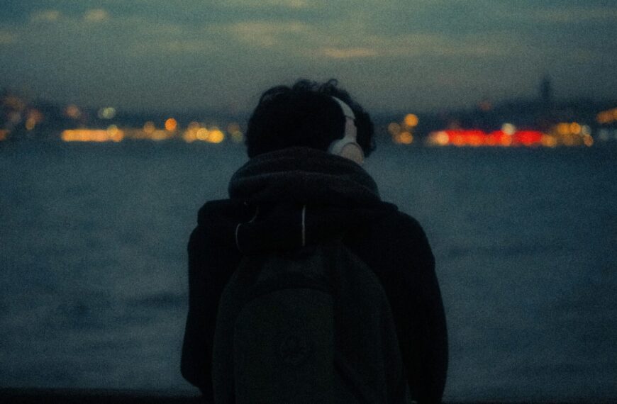 Backpacker wearing headphones overlooking water