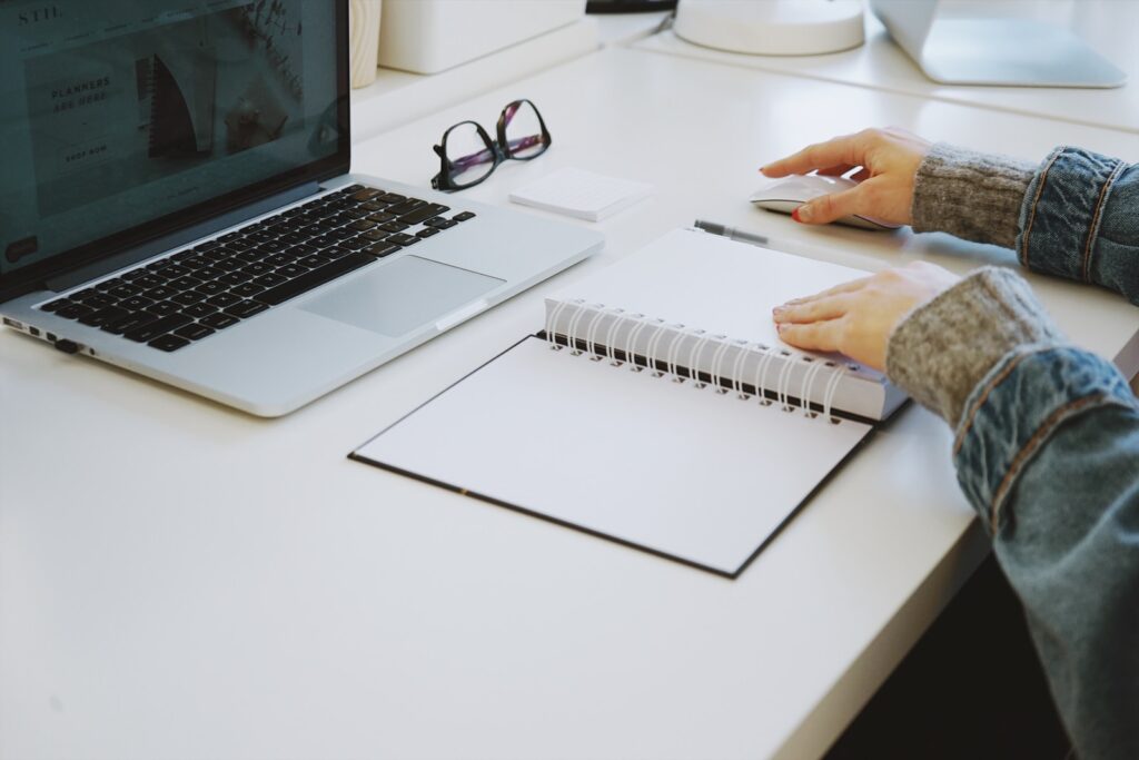 person touching white spiral notebook