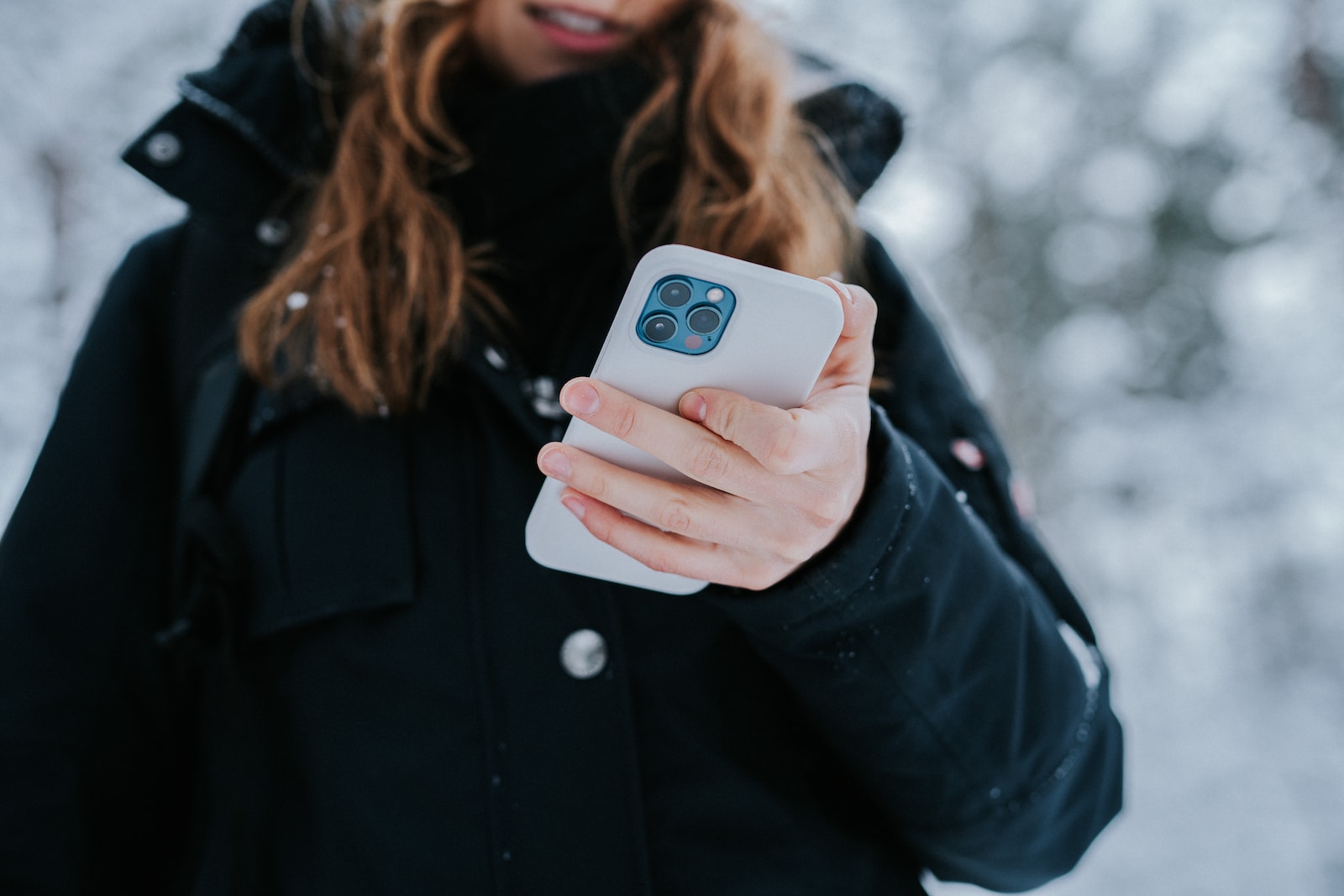 woman in black coat holding white and blue ceramic mug