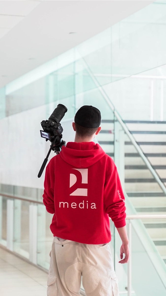 a man in a red hoodie is holding a camera