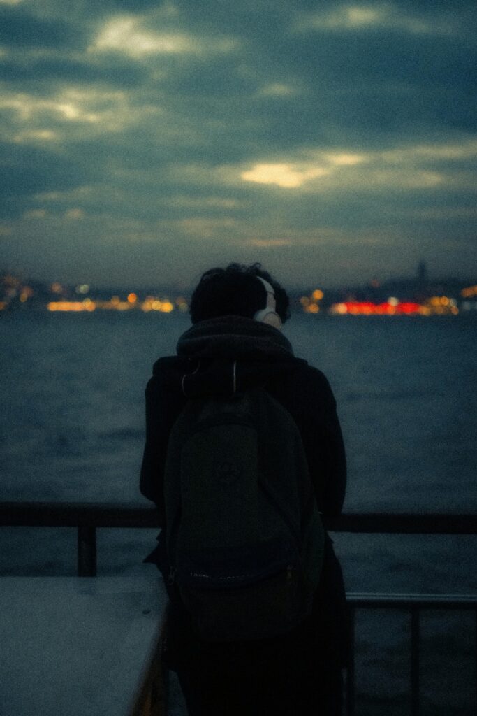 Backpacker wearing headphones overlooking water